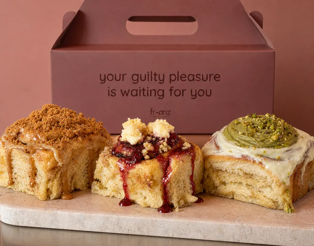 Box of three small cinnamon rolls in front of a fr-anz box